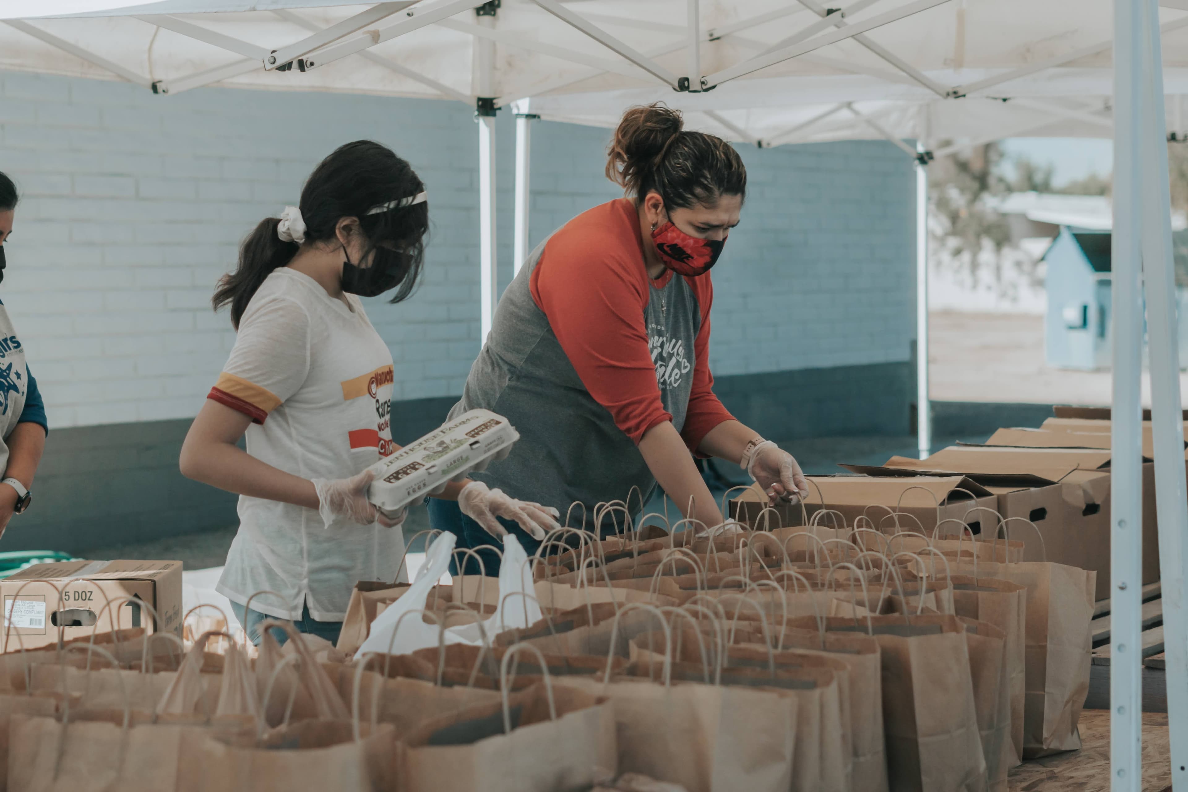 Two people filling bags with food for a distribution